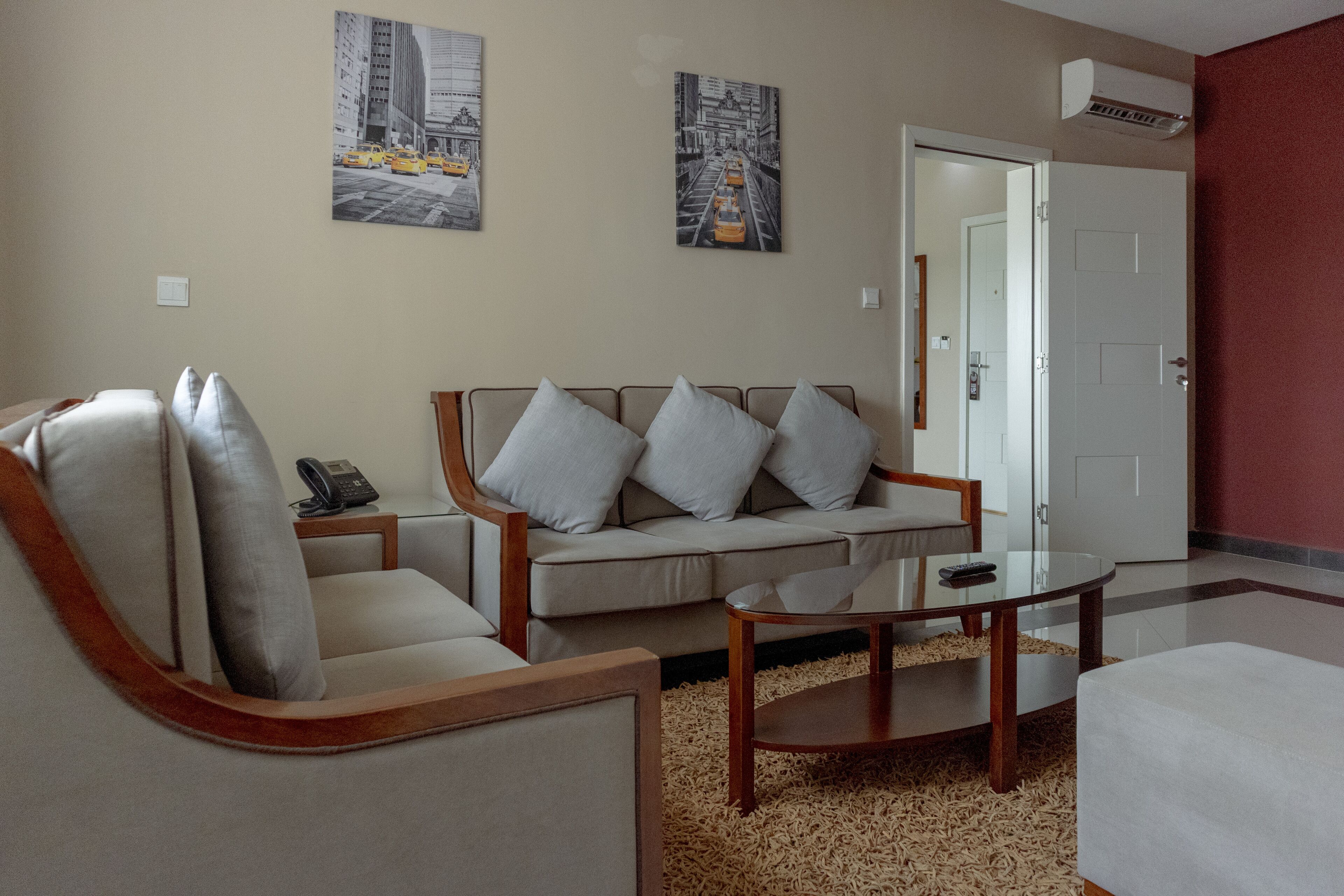 Una sala de estar con un sofá, sillones, una mesa de centro y dos cuadros colgados en la pared.