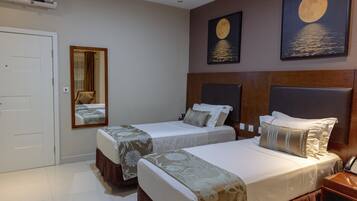 Habitación de hotel con dos camas, un espejo y una obra de arte que muestra la luna y el océano.