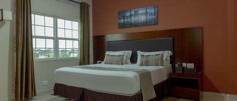 A bedroom with a large bed, a nightstand, an air conditioner, and a window with curtains.
