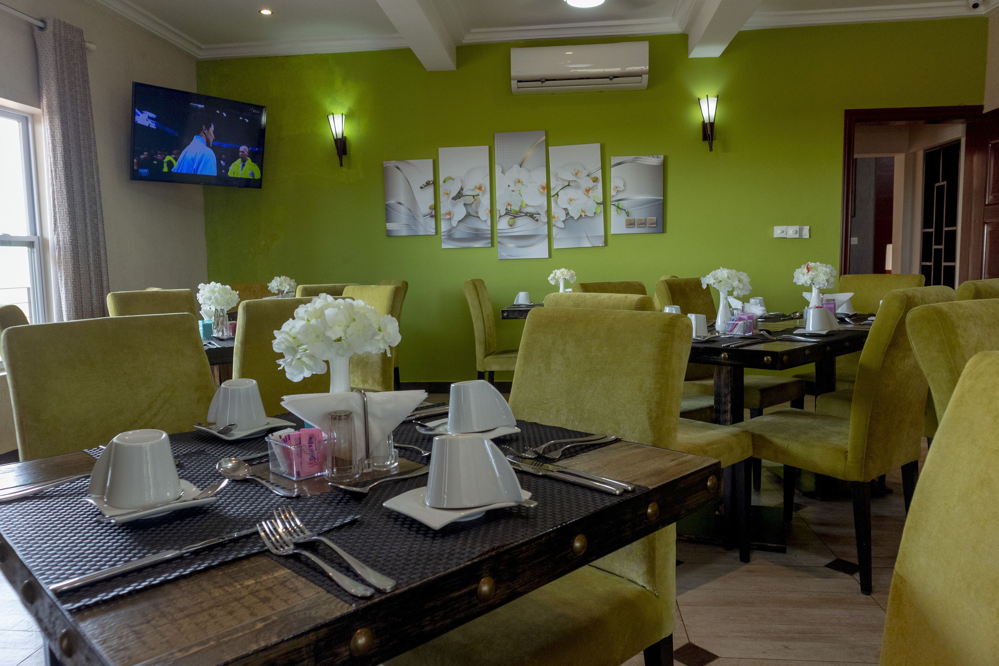A dining area with yellow chairs, a wooden table, and white tableware.