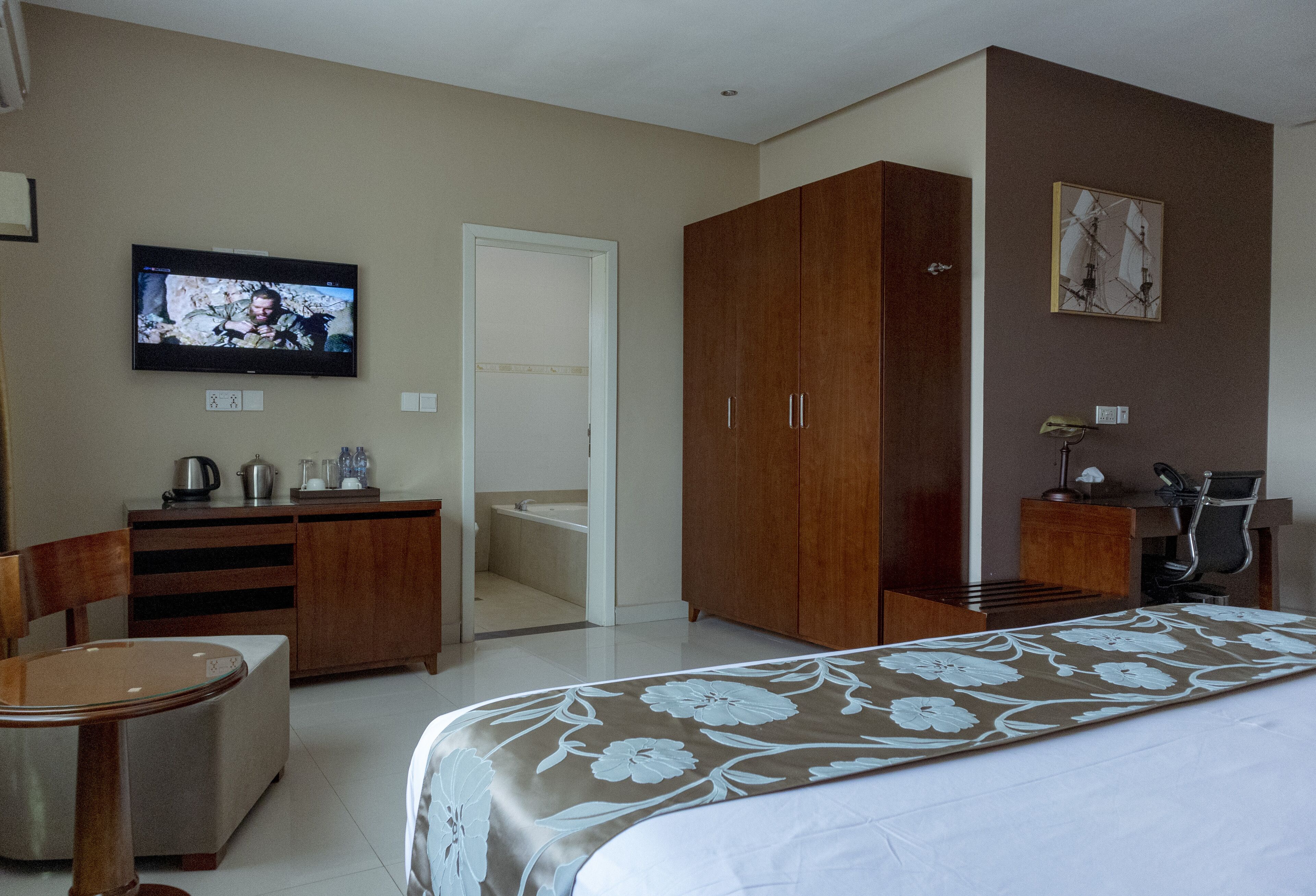 Una habitación de hotel con cama, televisión, escritorio, silla, armario y baño.