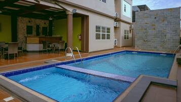 An indoor swimming pool with a tiled deck area, a bar, and a seating arrangement.