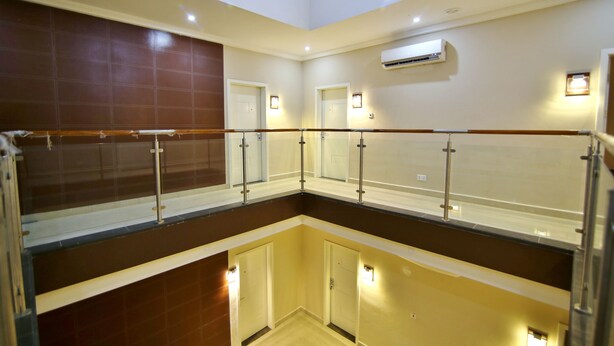 A hotel interior with a glass railing, a central air conditioning unit, and a tiled wall. - Frederick's Lodge (Kumasi)