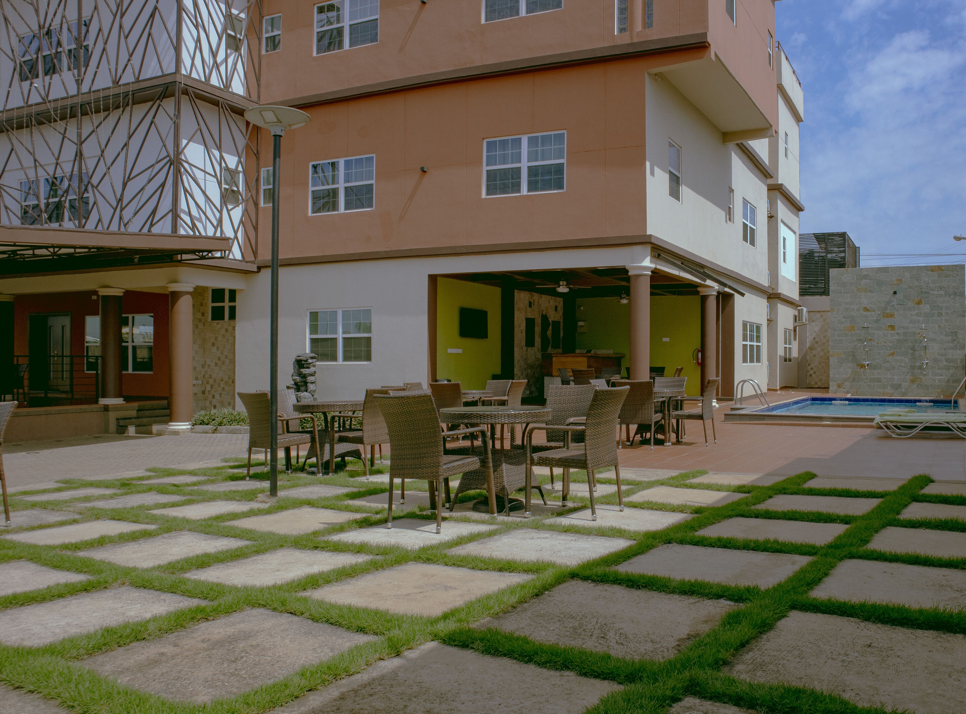 A multi-story building with a covered outdoor seating area, a pool, and a stone wall.