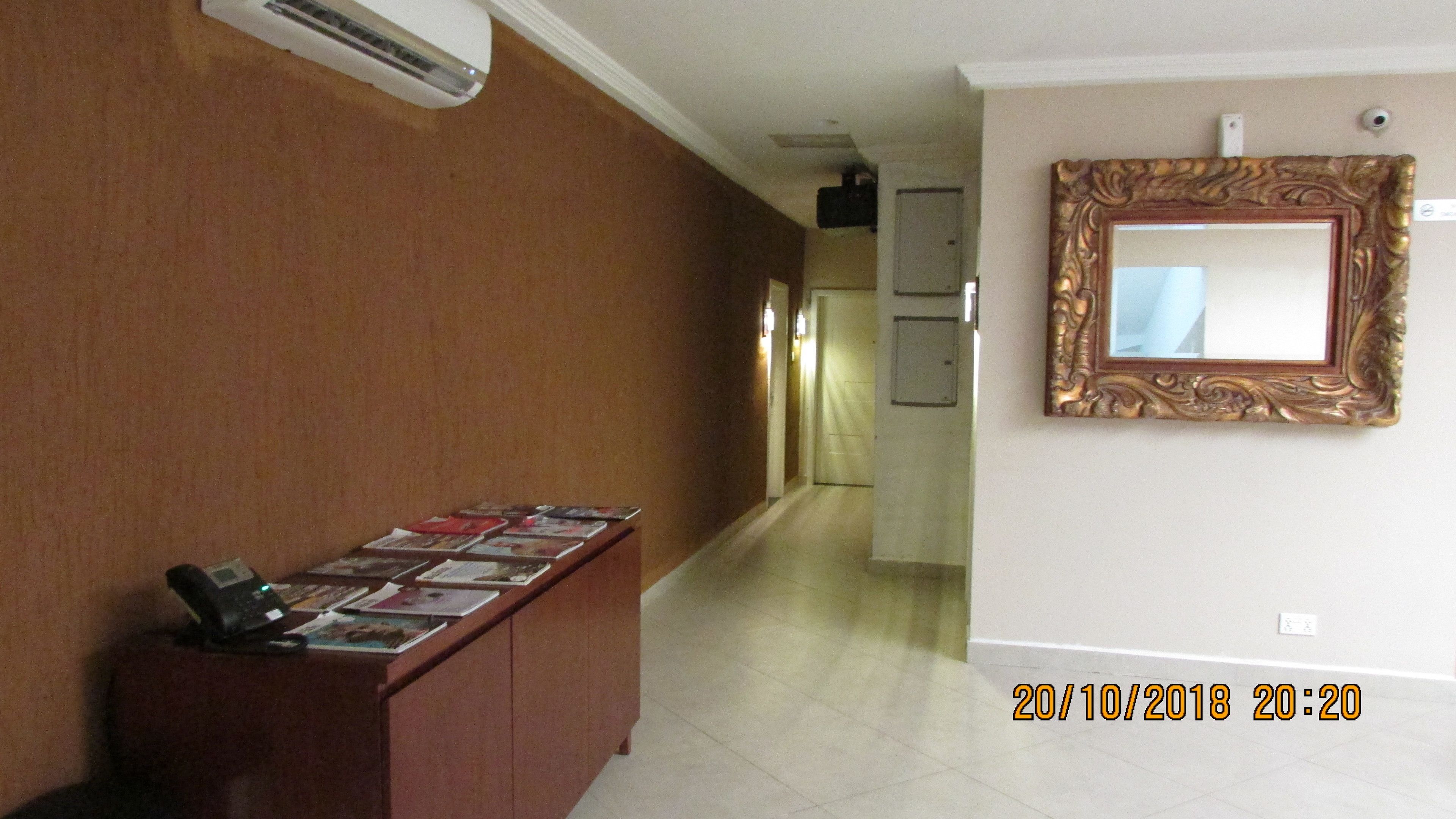 Un couloir avec un bureau en bois où sont exposés des magazines, un miroir fixé au mur et une porte au fond.