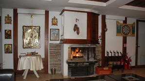 A living room with a fireplace, a dartboard, and various framed pictures on the walls.