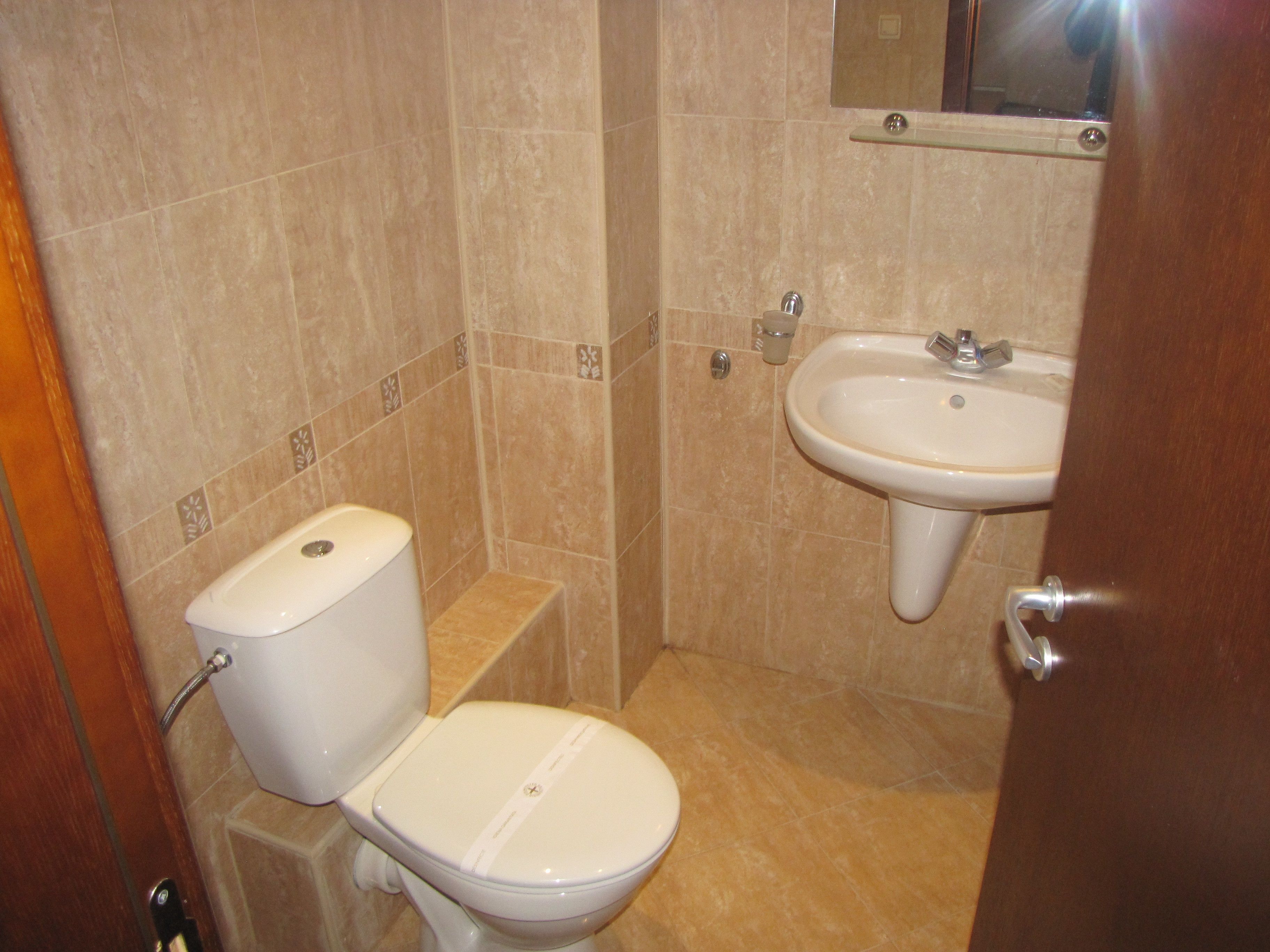 A small bathroom with a toilet, sink, and a mirror above the sink.