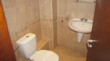Un baño pequeño con inodoro, lavamanos y espejo sobre él.