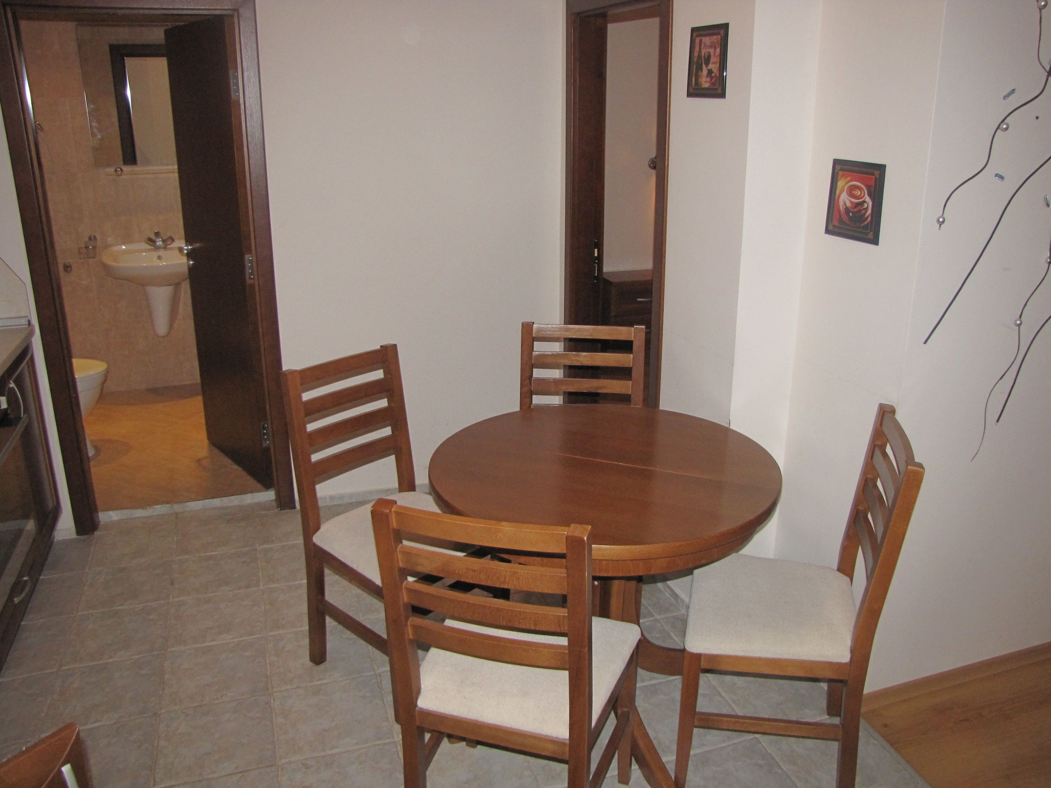 A dining area with a round wooden table and four wooden chairs with cushioned seats.