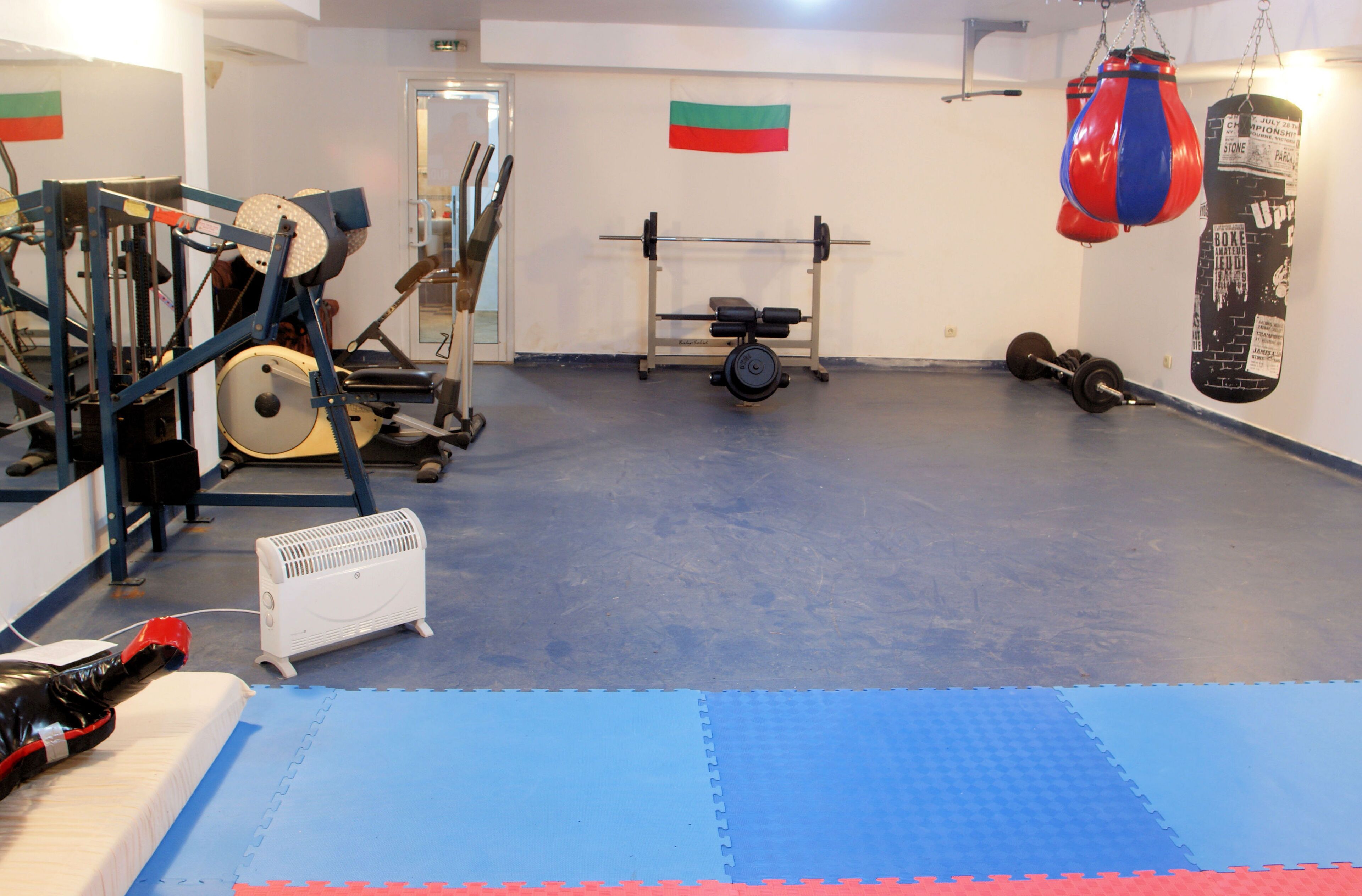 A gym with exercise equipment, a punching bag, and a weight bench.