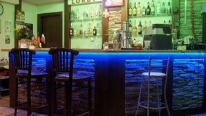 A bar area with a stone wall, wooden bar counter, and two wooden bar stools.