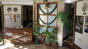 A reception area with a wooden desk, potted plants, and a wall with clocks and framed photos.