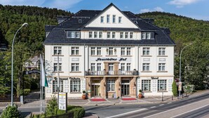 Un grand hôtel à deux étages, doté d’une entrée imposante, de nombreuses fenêtres et d’un balcon.