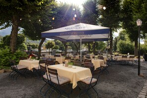 Un área de comedor al aire libre con mesas y sillas bajo una cubierta.