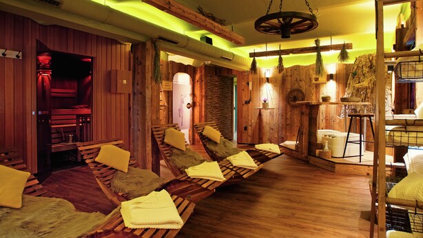 Un sauna avec des bancs en bois, un mur en bois et un mur en pierre.