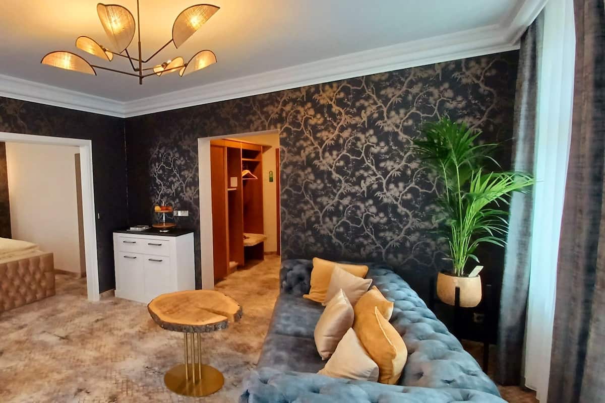 A bedroom with a bed, a sofa, a round wooden table, and a wardrobe.