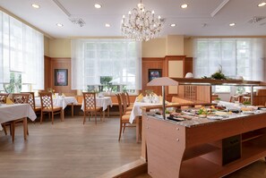 Un restaurante con mobiliario de madera, una isla central con comida y ventanas amplias.