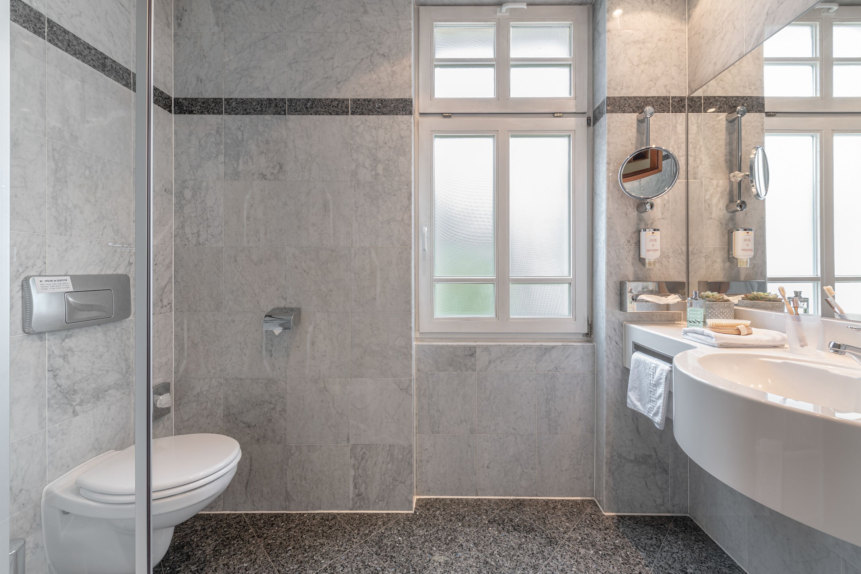 Une salle de bain moderne avec une douche à parois de verre, des toilettes blanches et une grande baignoire sur pieds.