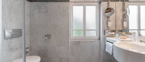 A modern bathroom with a glass-enclosed shower, a white toilet, and a large freestanding bathtub.