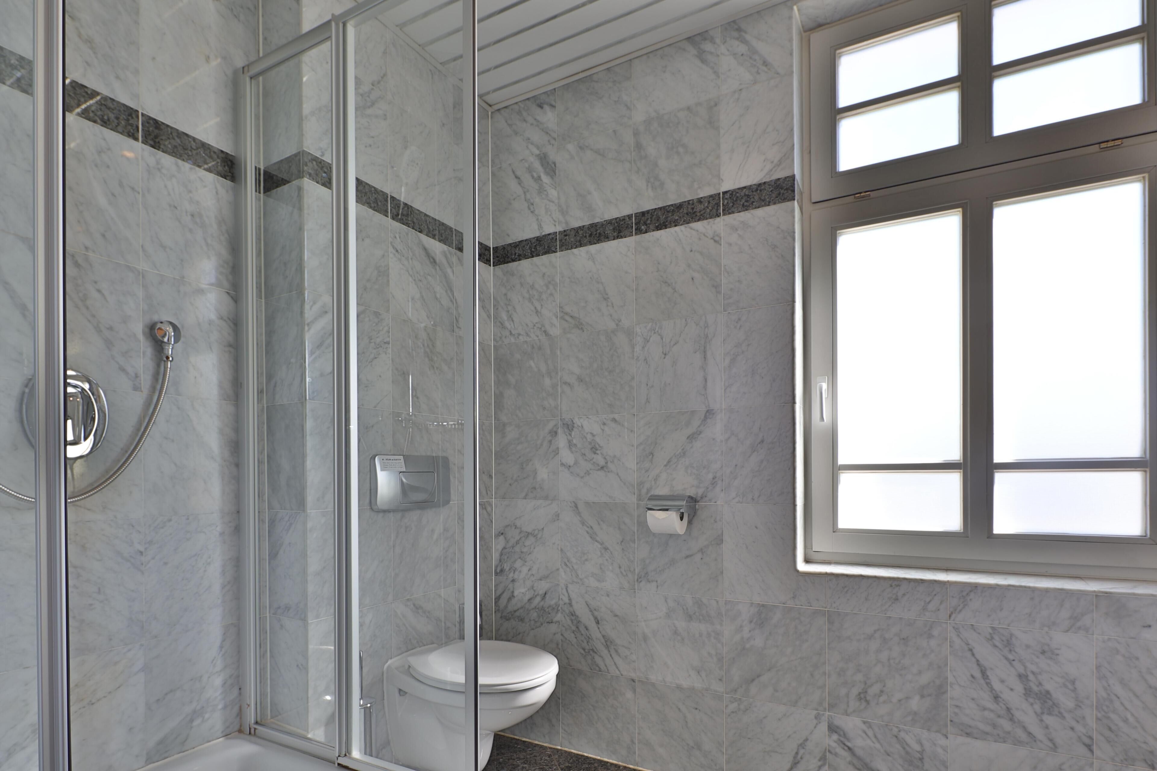 Un baño moderno con ducha de vidrio, inodoro y ventana.