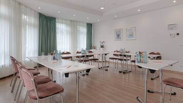 A conference room with white tables, brown chairs, and a large window with green curtains.