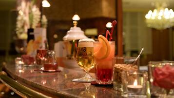 A bar area with various drinks and glasses, including a tall glass with a lemon garnish and a smaller glass with a red drink and a straw.