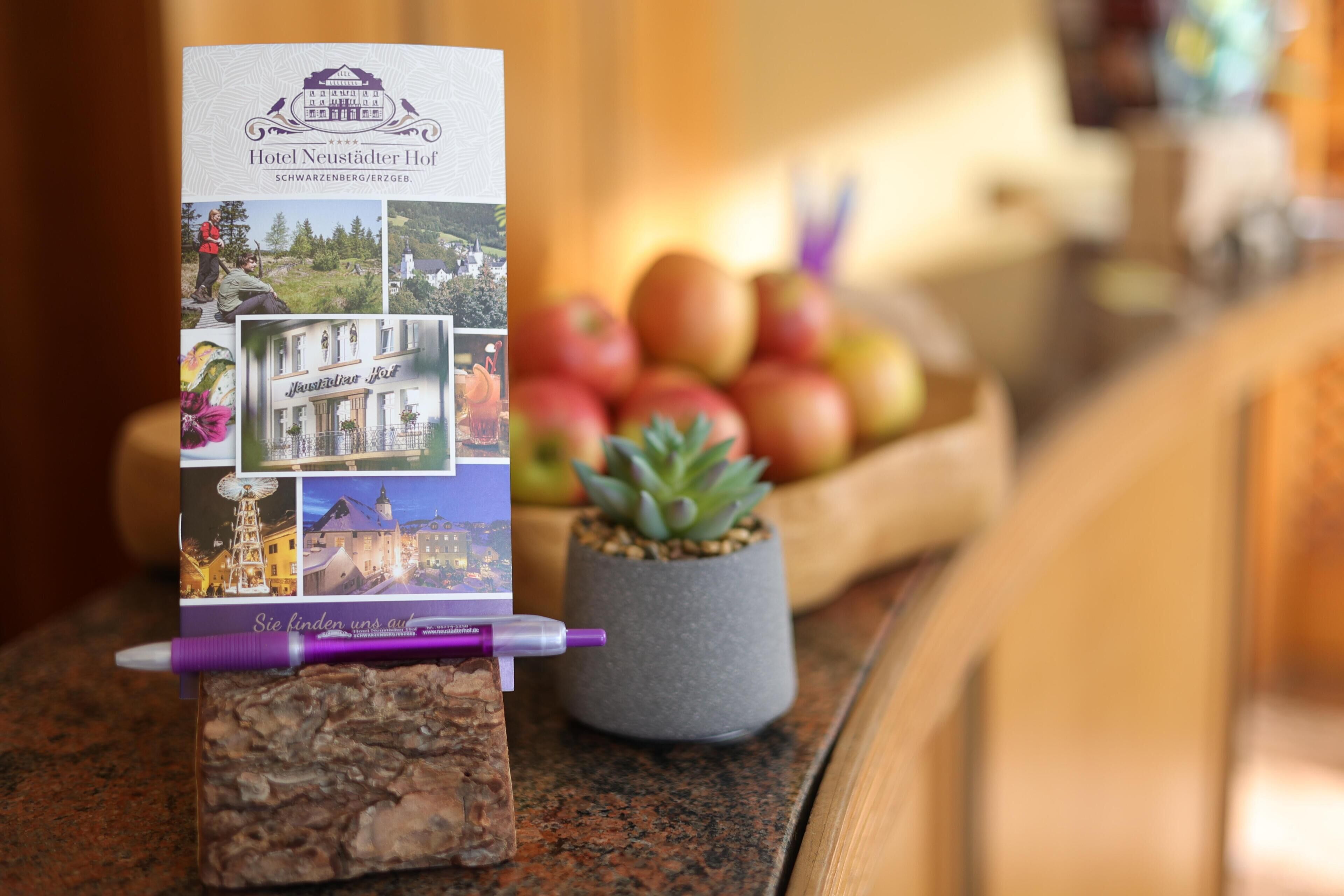 A brochure for Hotel Neustädter Hof, featuring a scenic view of the hotel and a small succulent plant on a countertop.