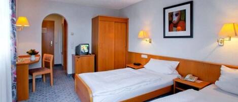 Habitación de hotel con dos camas, un escritorio, una silla, un armario y un cuadro en la pared.