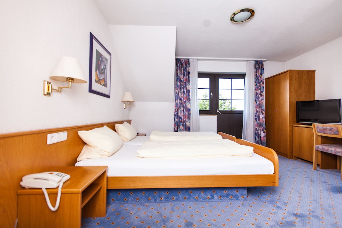 Una habitación de hotel con cama, mesita de noche con teléfono, televisión y armario.