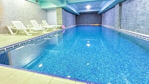 Una piscina interior con agua azul cristalina, rodeada de paredes de textura similar a la piedra.
