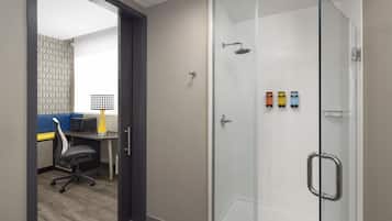 Un baño moderno con cabina de ducha de vidrio, un escritorio con silla y un papel tapiz estampado.