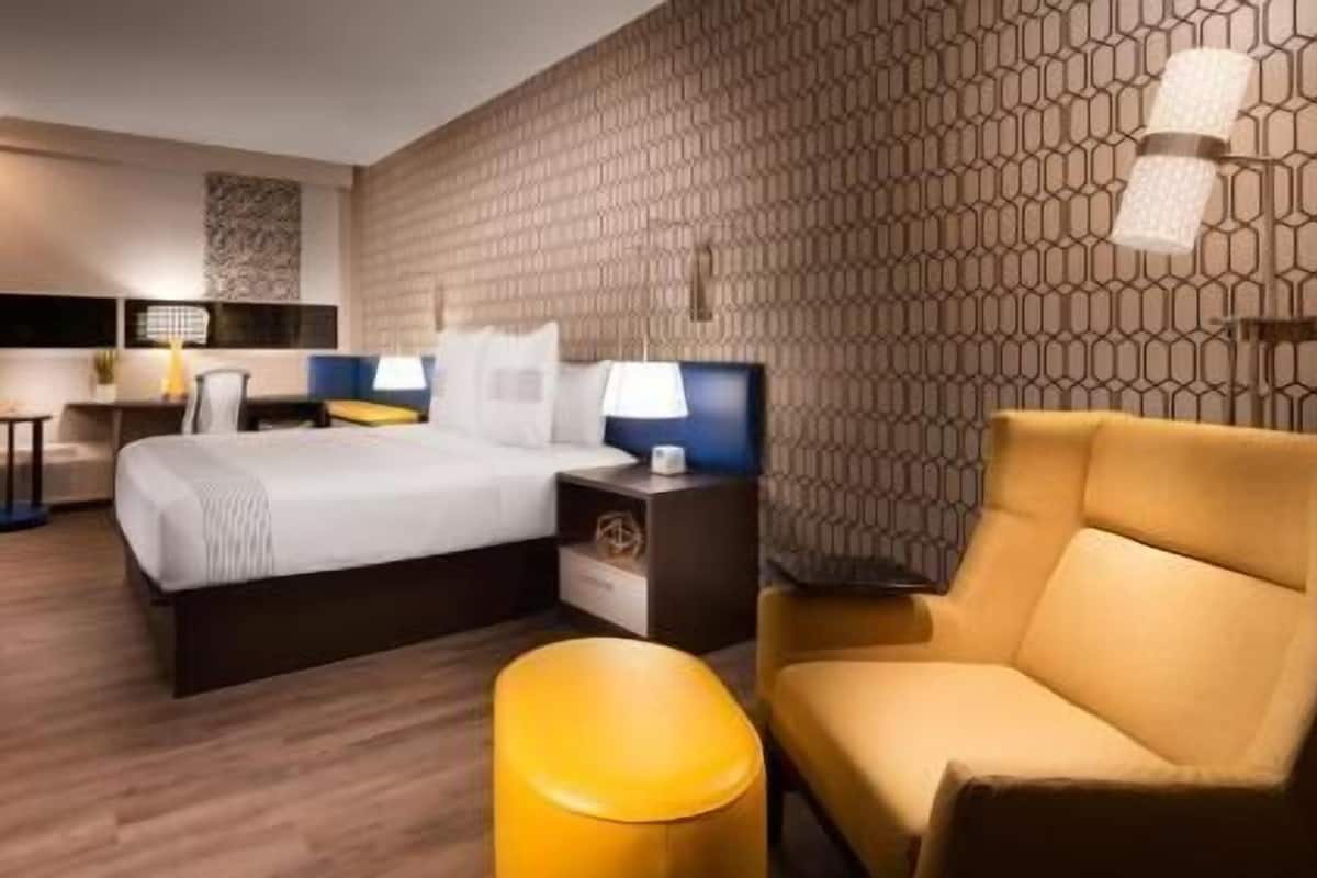 Una camera d'albergo con un letto, comodini, una sedia e una parete decorata.
