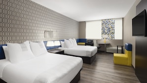 Hotellihuone, jossa on kaksi sänkyä, työpöytä, tuoli ja televisio.