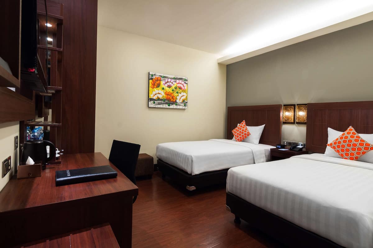 A hotel room with two beds, a desk, a coffee machine, and a painting on the wall.
