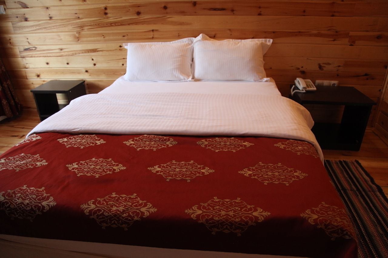 Una habitación con paneles de madera, una cama, dos mesitas de noche y un teléfono.
