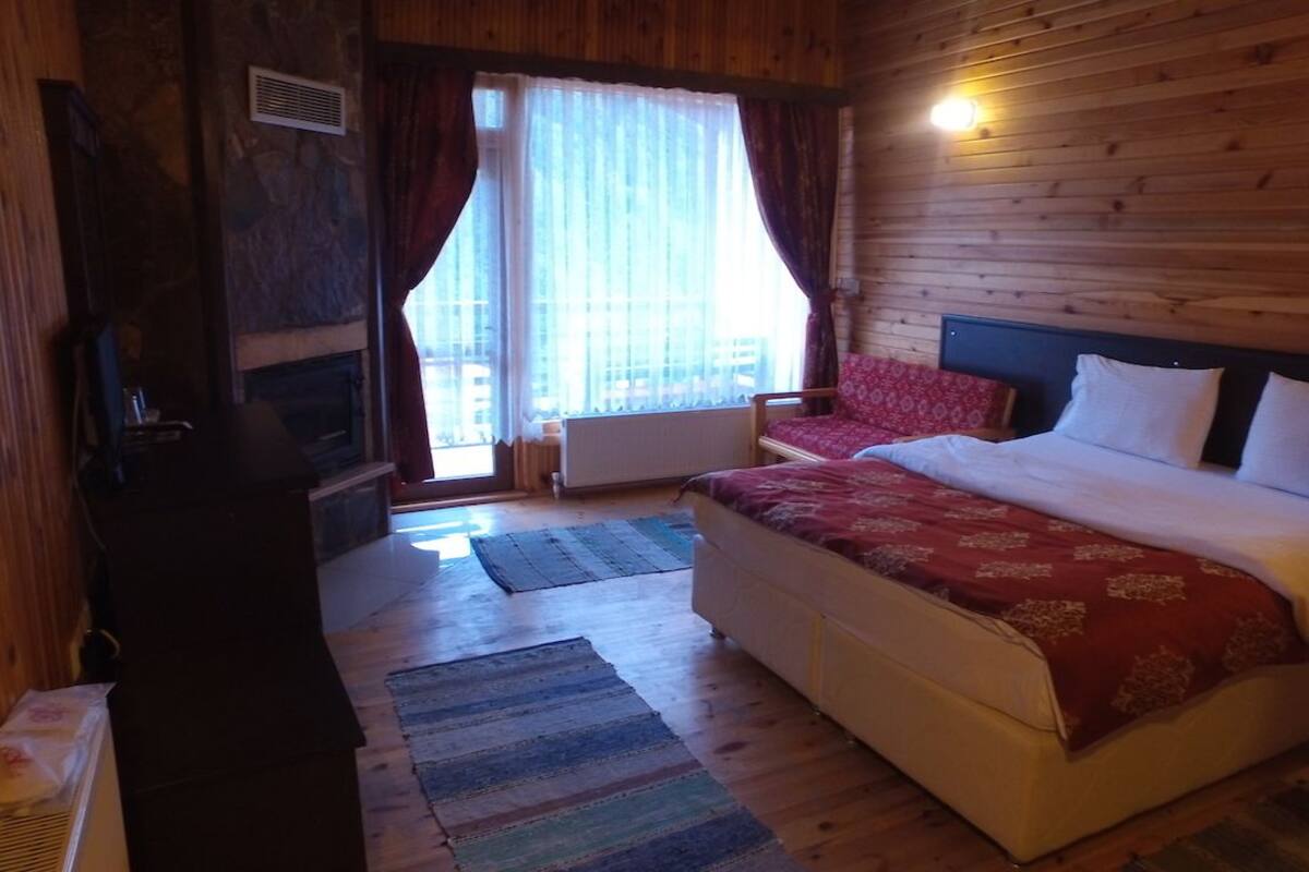 Ein gemütliches Zimmer mit einem Bett, Kamin und Blick ins Freie.