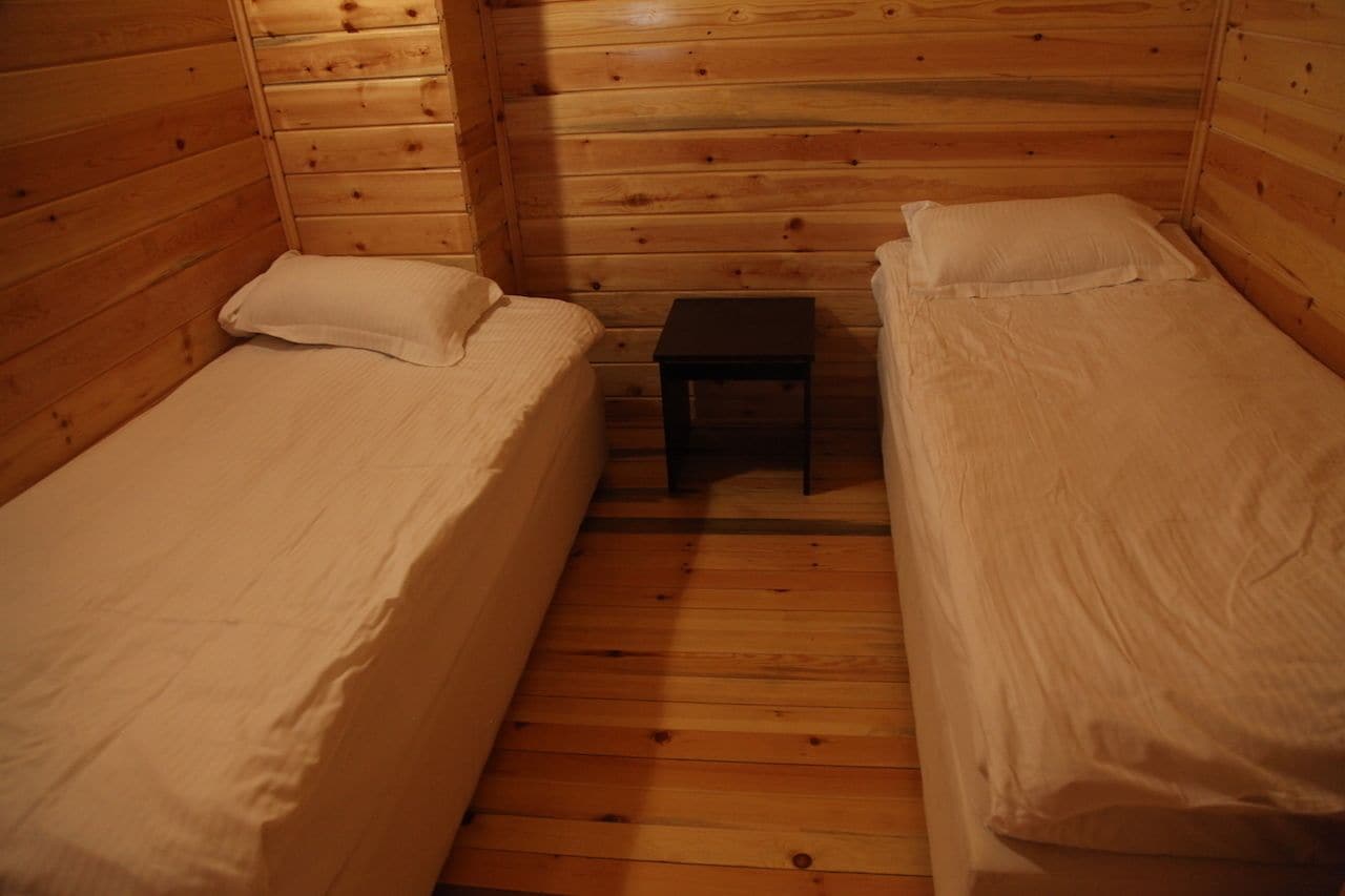 A cabin with two wooden bunk beds, a small table, and a wooden floor.