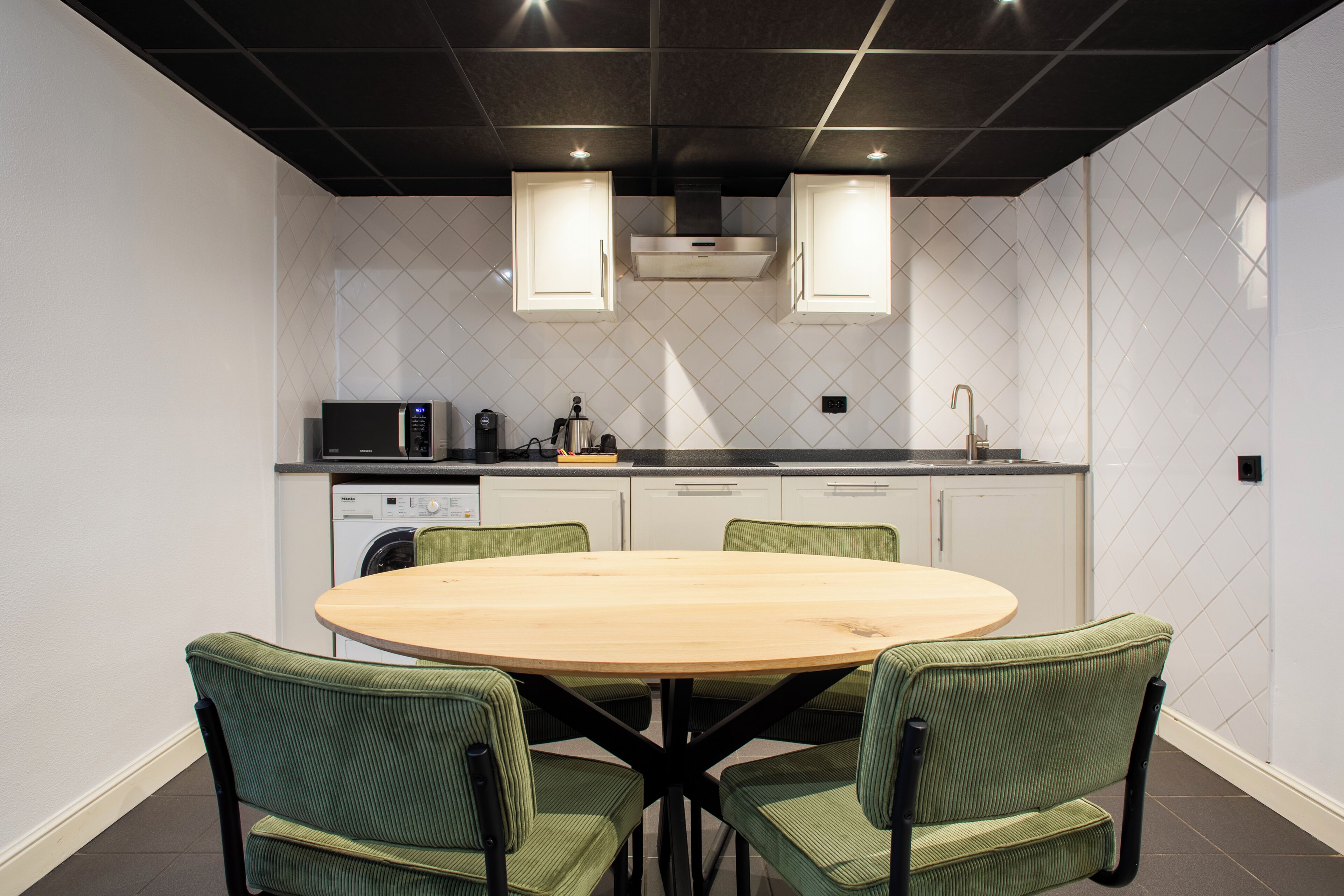 Une cuisine moderne avec un coin repas, comprenant une table ronde et quatre chaises, un lave-vaisselle et un four à micro-ondes.
