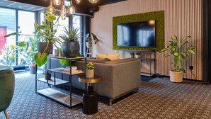 A modern living room with a grey sofa, a flat-screen TV mounted on a green wall, and multiple hanging light fixtures.