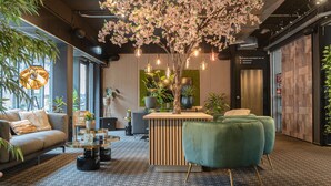 A modern interior with a reception desk, seating area, and decorative plants.