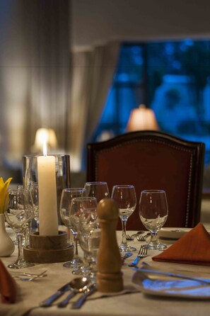 Una mesa de comedor dispuesta con varias copas de vino, una vela y cubiertos.