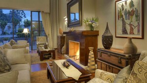 Un salón amplio con chimenea, asientos cómodos y ventanas grandes que ofrecen vistas al exterior.