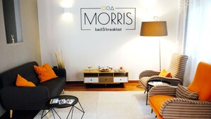 Ein modernes Wohnzimmer mit Sofa, Sessel, Couchtisch, einer Anrichte und einer Lampe.