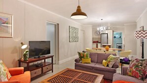 Ein modernes Wohnzimmer mit Fernseher, Sofa, Couchtisch und dekorativen Kissen.