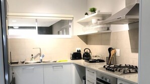 Eine moderne Küche mit weißen Schränken, einem eingebauten Ofen, einem Gasherd und einer kleinen Kochinsel mit Spüle.