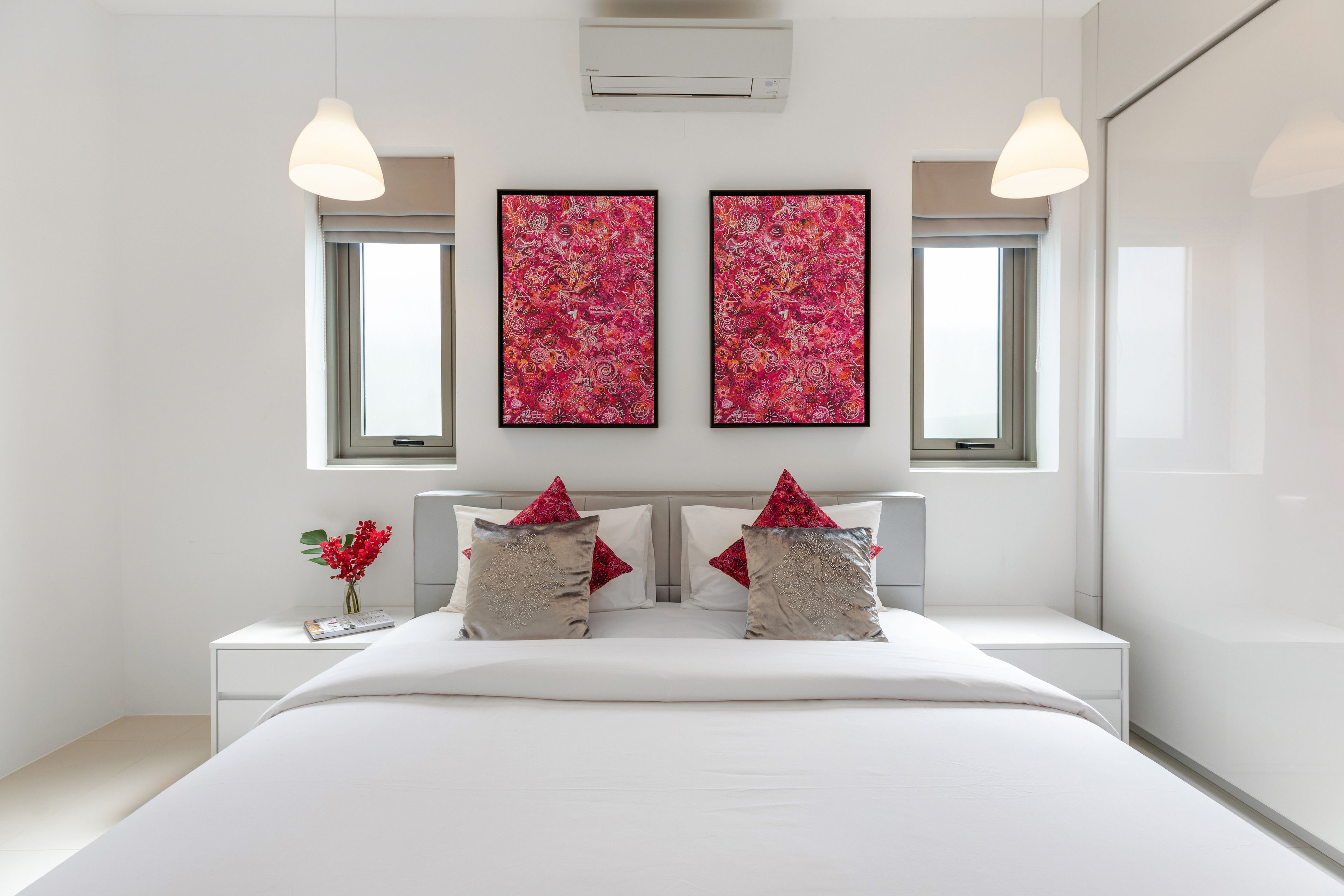 A modern bedroom with a large bed, two bedside tables, and two wall-mounted air conditioning units.