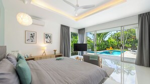 Quarto moderno com uma cama grande, uma televisão e vista para uma piscina.