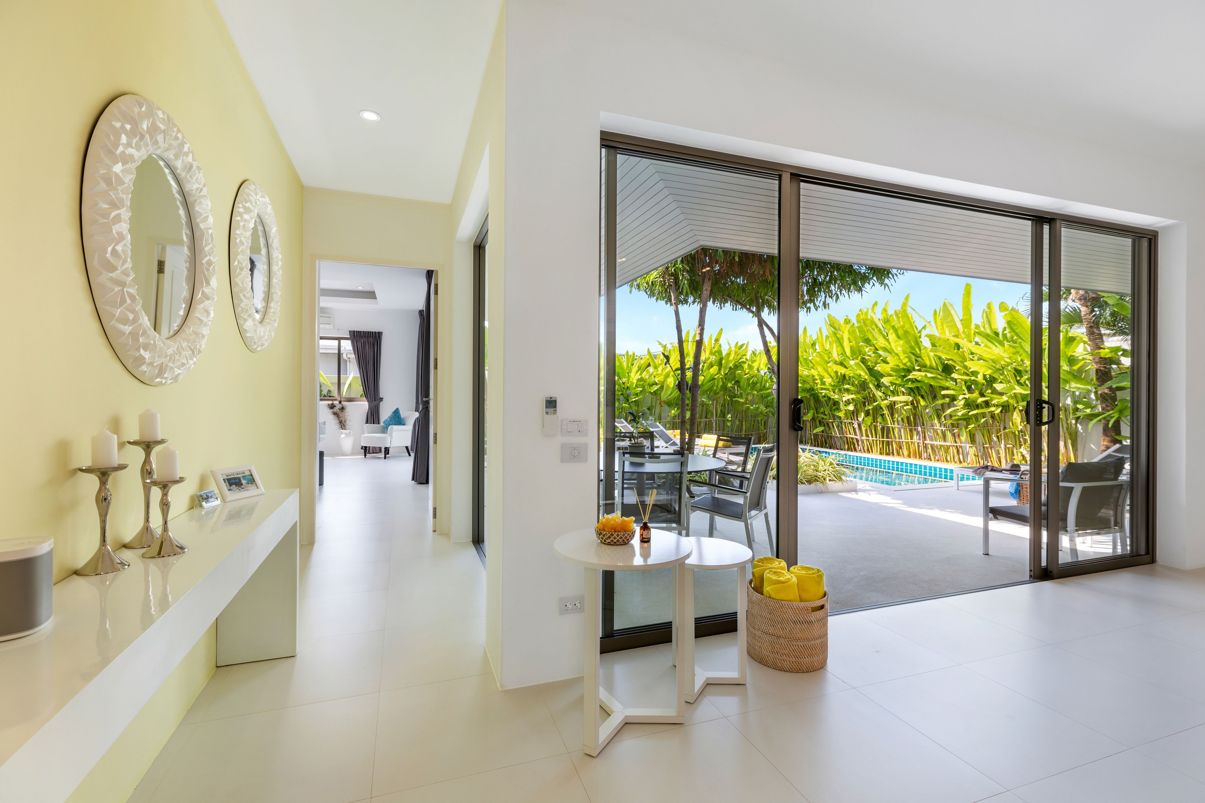 A modern interior with a reception desk, decorative mirrors, and a view of an outdoor pool area.