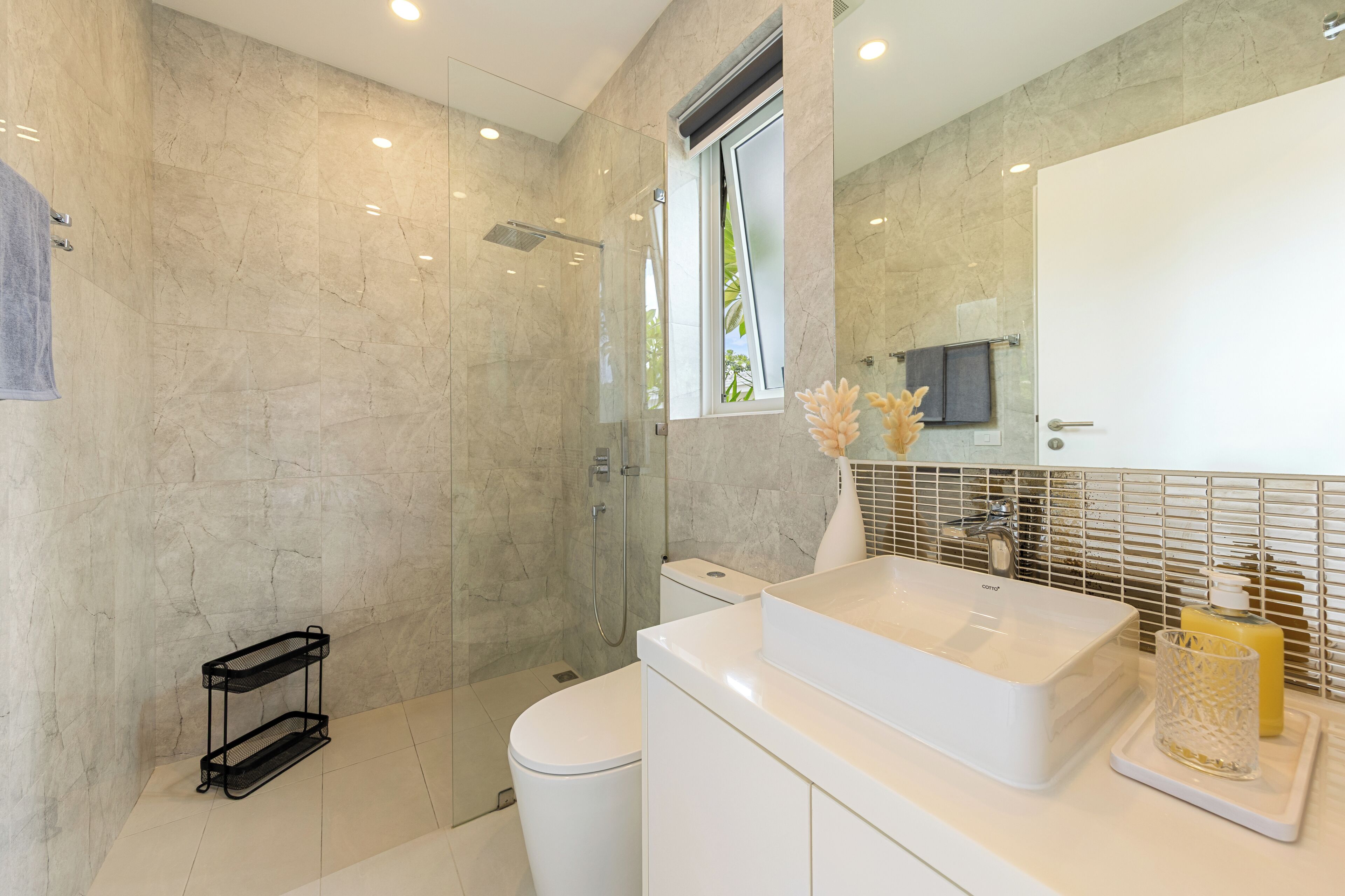 Un baño moderno con cabina de ducha de vidrio, un lavabo blanco y un inodoro.