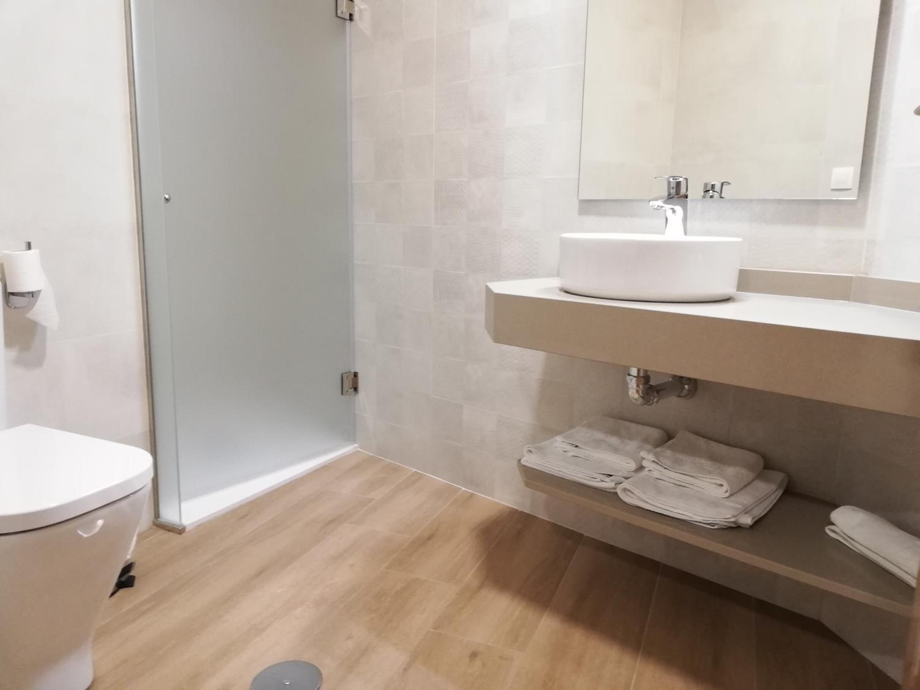 A modern bathroom with a toilet, a sink, and a shower.